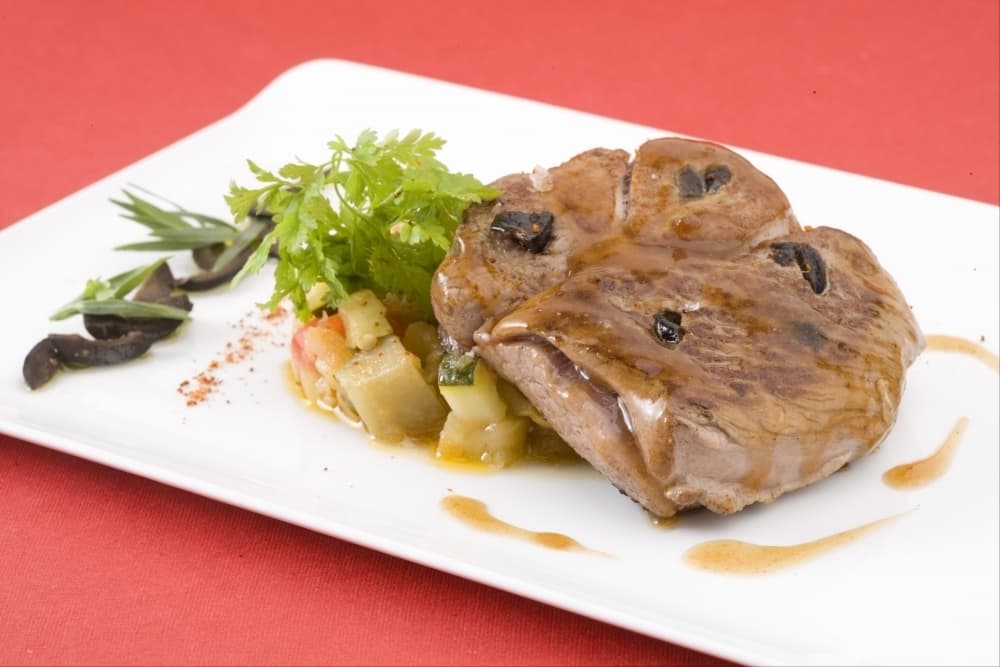 Gigotin d'agneau rôti au jus et piqué aux olives noires, cocotte de légumes au piment d'Espelette