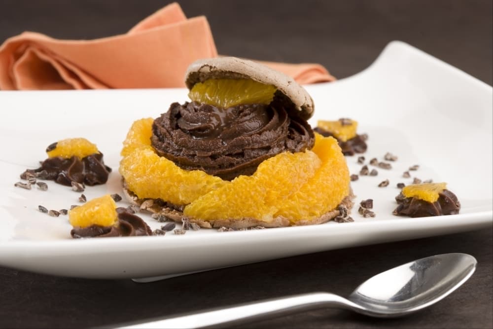 Macaron au chocolat, ganache mousseuse au lait et segments d'orange