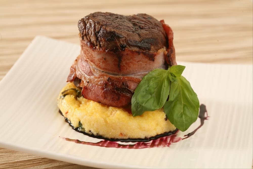 Tournedos de boeuf au lard fumé, galet de polenta au basilic et tomates confites