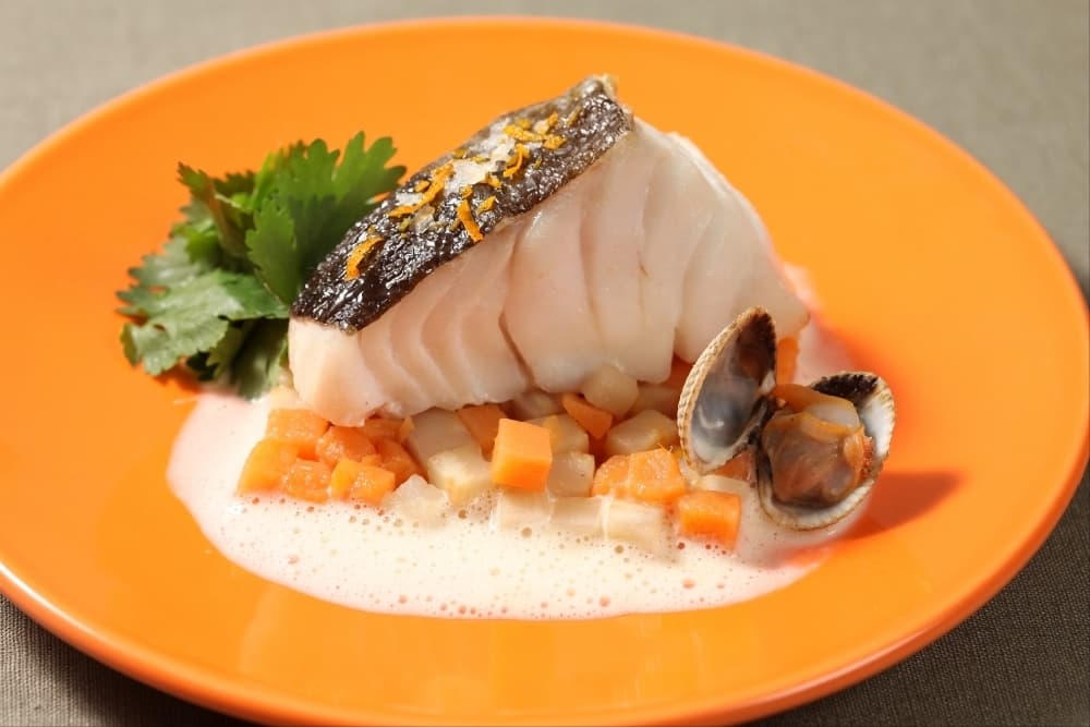 Pavé de cabillaud à la fleur de sel orangée, patate douce et céleri-rave étuvés, jus de coques crémé