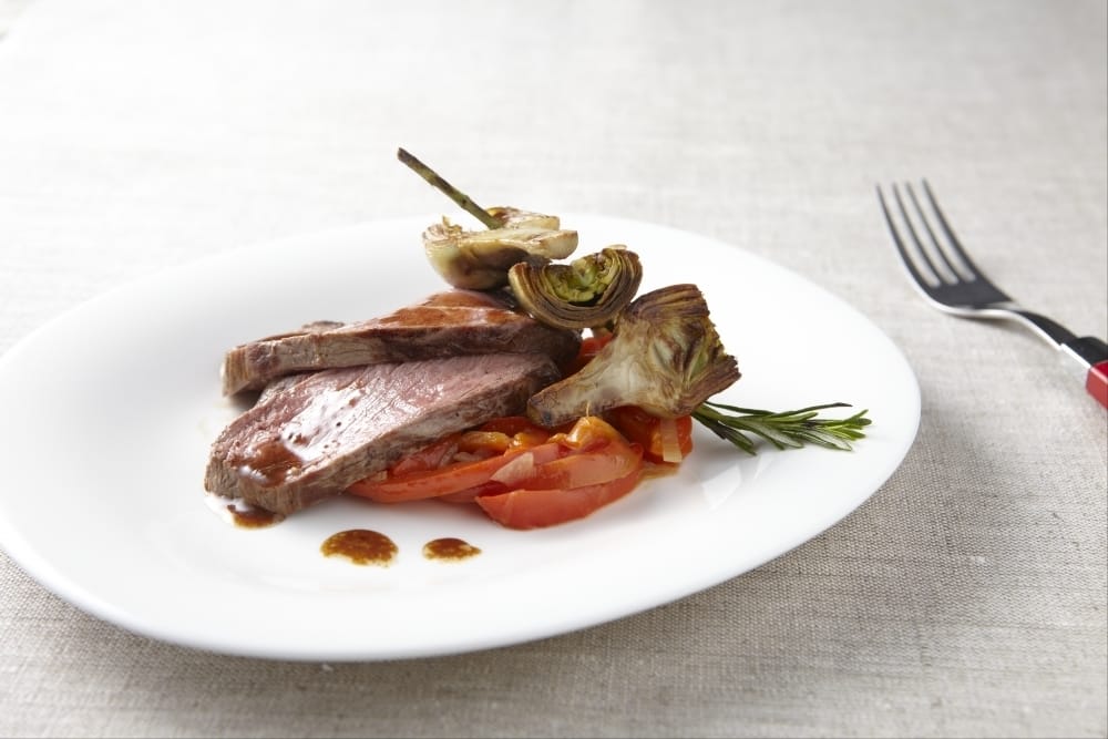 Gigot d'agneau rôti à la fleur de sel, artichauts poivrades et poivrons doux