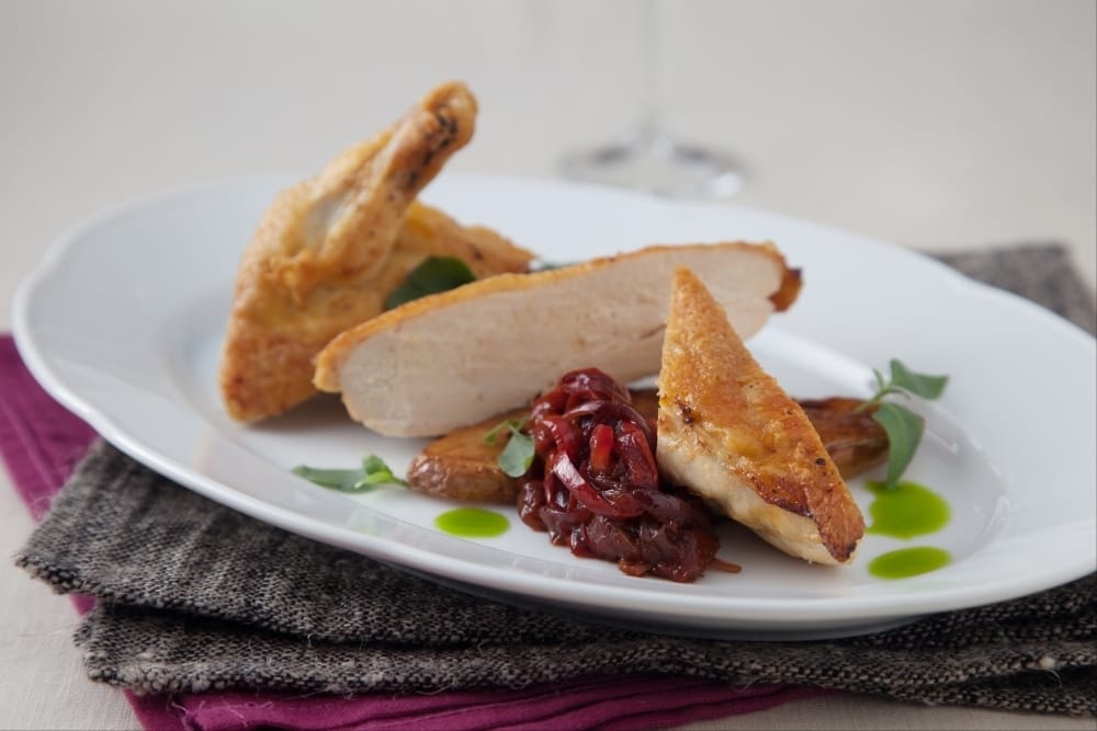Suprême de poulet jaune et sa poivronnade, pommes de terre confites à l'origan et huile de basilic